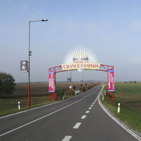 Ein bunter Bogen über einer Landstraße, der einen festlichen Eingang markiert.