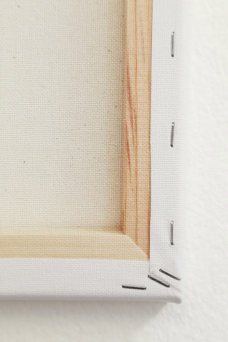 Eckansicht einer leeren Leinwand mit sichtbaren Heftklammern und Holzrahmen.