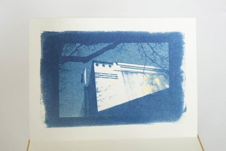 Blaues Bild eines Gebäudes mit Baumästen im Vordergrund.