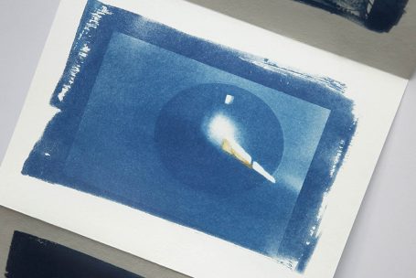 Ein blauer Druck zeigt einen Lichtstrahl, der aus einem Kreis strahlt.