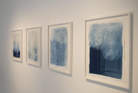 Vier gerahmte Aquarelle in Blau- und Grautönen an einer Wand.