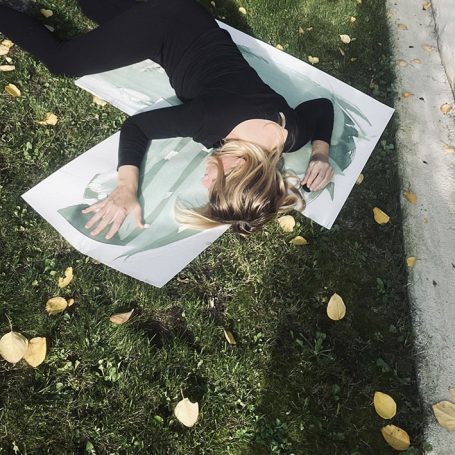 Eine Person liegt auf dem Boden und zeichnet auf ein großes Blatt Papier.