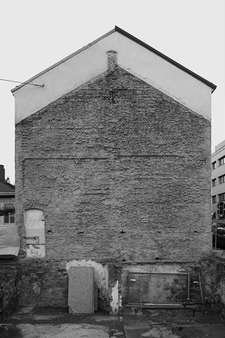 Hinteransicht eines Gebäudes mit Steinwand und einfachen Materialien.
