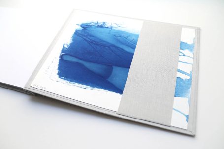 Buch mit grauem Einband und blauer abstrakter Illustration auf der Vorderseite.