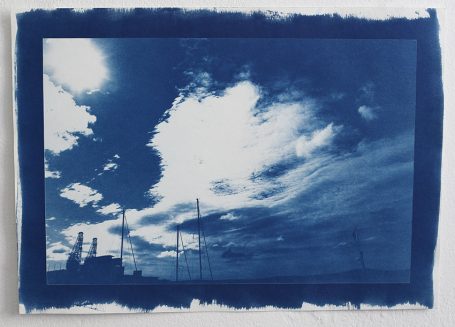 Himmel mit Wolken in Blau- und Grautönen, mit silhouettierten Maststrukturen.