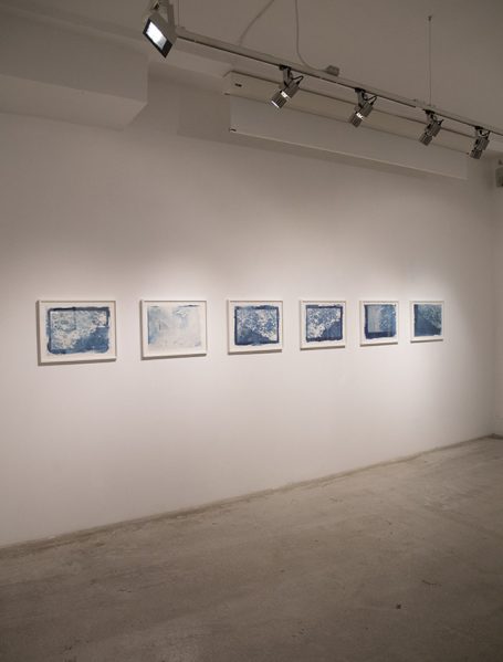 Galerie mit mehreren Bildern in weißen Rahmen an einer hellen Wand.