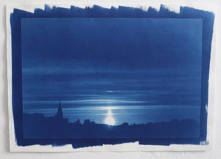 Blaustich eines Sonnenuntergangs über ruhigem Wasser mit silhouettierten Hügeln.