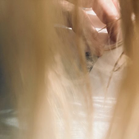 Helle Haare und Hände, die eine transparente Fläche berühren.
