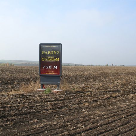 Ein Schild zeigt "Party: Ca. 750 m" auf einem leeren, bearbeiteten Feld.