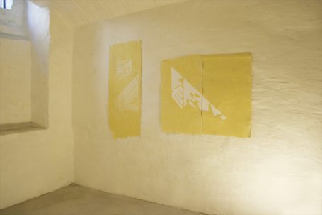 Zwei gelbe Leinwände an einer weißen Wand in einem Raum.