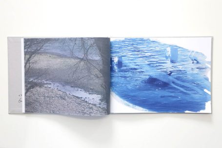 Ein aufgeschlagenes Buch mit einer Landschaftsillustration und blauer Farbfläche.