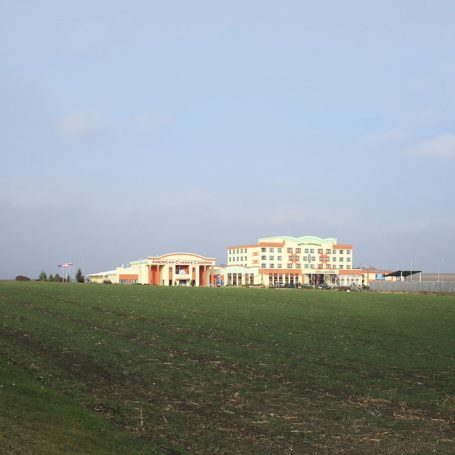 Moderne Gebäude auf einem weitläufigen, grünen Feld unter einem bewölkten Himmel.