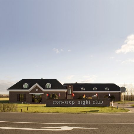 Ein Nachtclub mit einem modernen Gebäude und Fahnen vor einem klaren Himmel.