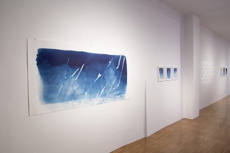 Abstrakte blaue Kunstwerke in einer hellen Galerie mit Holzfußboden.
