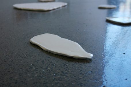 Weißer, flacher Ton auf einer dunklen, glatten Oberfläche.