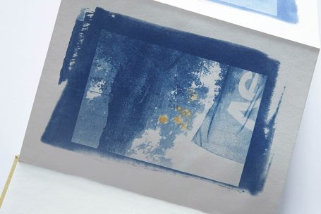 Abstrakte blaue Komposition mit gelben und weißen Akzenten auf grauem Hintergrund.