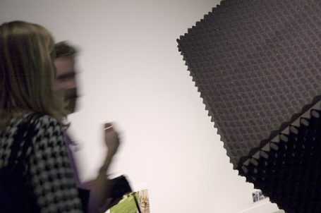 Zwei Personen stehen vor einer abstrakten Kunstinstallation in einem klaren Raum.