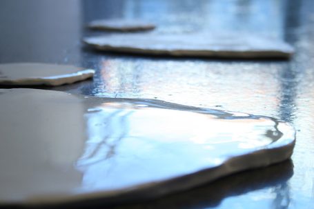 Wässrige Substanz auf einer reflektierenden Oberfläche, mit glatten, flachen Formen.