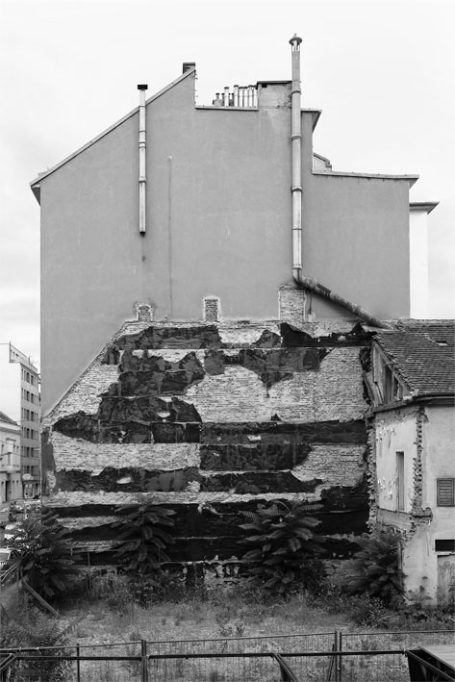 Einsturzgefährdetes Gebäude mit abblätternder Fassade und grauem Hintergrund.