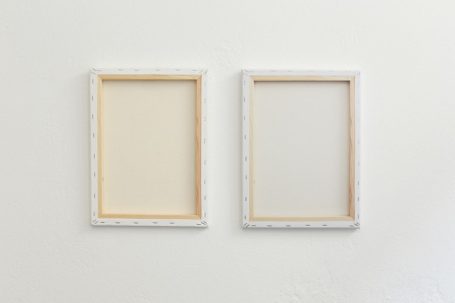 Zwei leere Bilderrahmen an einer weißen Wand, einer mit hellen und einer mit dunklen Kanten.