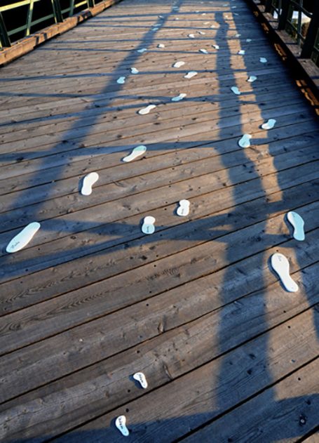 Schuhabdrücke auf einem Holzboden, von Schatten umgeben.