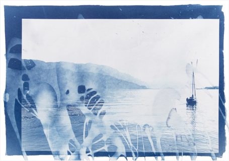Fußabdrücke im Sand am Ufer eines Sees mit einem Boot und hügeliger Landschaft im Hintergrund.