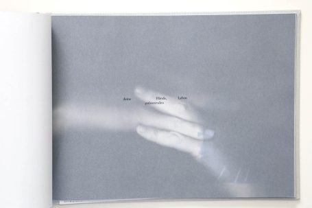Eine verschwommene Hand auf grauem Hintergrund mit unscharfen Textfeldern.