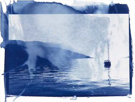 Ein Segelboot fährt ruhig auf einem blauen Gewässer, umgeben von Hügeln.
