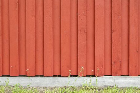 Rote Holzvertäfelung mit Gras am unteren Rand.