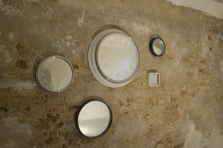 Verschiedene Spiegel in verschiedenen Größen an einer rustikalen Wand.