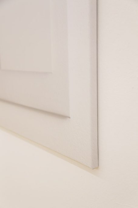 Weiße Tür mit glatter Oberfläche, leicht schattiert, an einer hellen Wand.