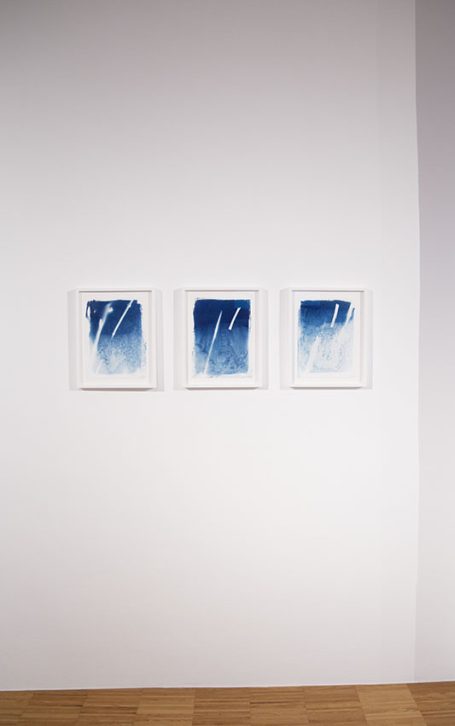 Drei gerahmte Bilder mit blauen Farbverläufen an einer weißen Wand.
