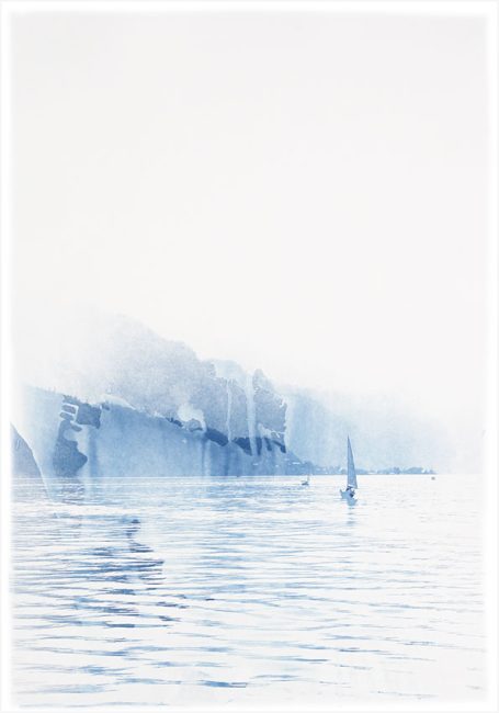 Ein sanfter, blauer Horizont mit nebligen Klippen über ruhigem Wasser.