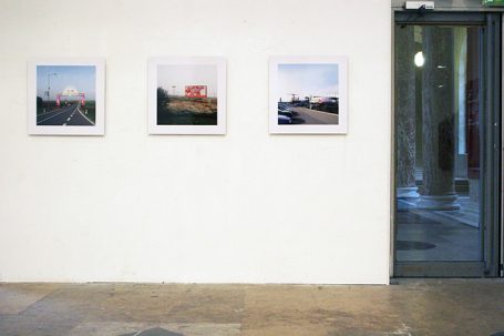 Drei gerahmte Fotos an einer weißen Wand neben einer Glasschiebetür.