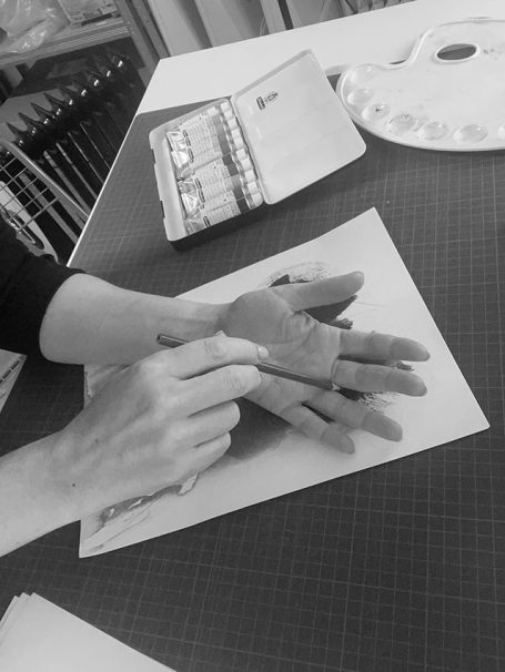 Eine Hand malt mit einem Pinsel auf einer Papierplattform.