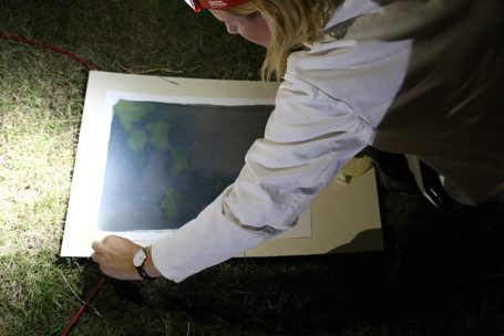 Eine Person beleuchtet eine Karte auf dem Boden mit einer Taschenlampe.