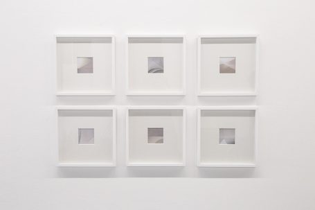 Sechs quadratische Bilder in weißen Rahmen an einer weißen Wand.