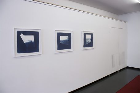 Drei gerahmte Bilder in blauen Farbtönen an einer weißen Wand.