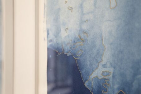 Helle blaue Wand mit goldenen Akzenten und abstraktem Muster.