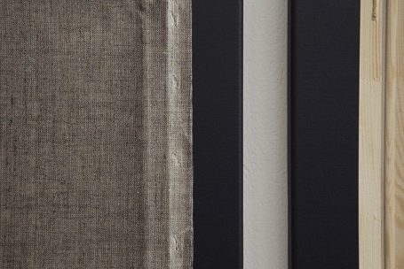 Texturen in neutralem Farbton: graues Gewebe, schwarze und helle Holzplatten.
