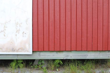 Rote Wand mit vertikalen Holzlatten und einem weißen, abgenutzten Bereich.
