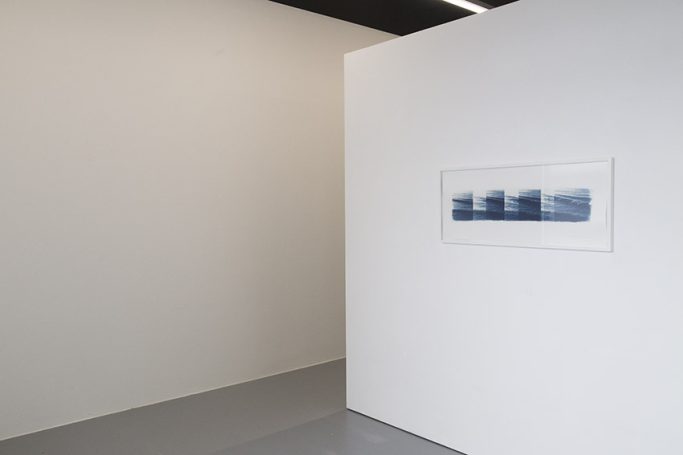 Ein minimalistischer Ausstellungsraum mit einem blauen Kunstwerk an der Wand.