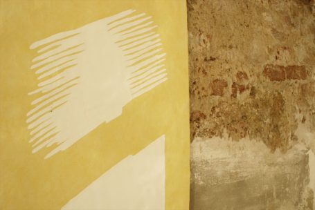 Weißer Pinselstrich auf gelbem und braunem unregelmäßigem Hintergrund.
