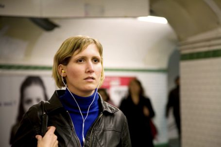 Frau mit Kopfhörern in einer U-Bahn-Station, konzentriert und in Bewegung.
