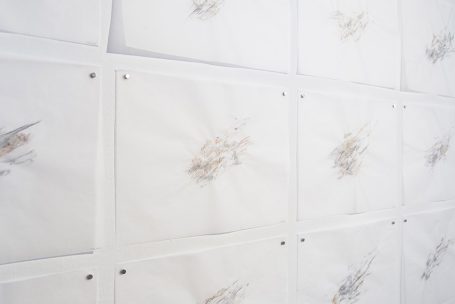 Texte auf weißen Blättern, an einer Wand angepinnt, mit schematischen Zeichnungen.