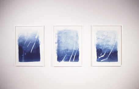 Drei gerahmte abstrakte Kunstwerke in verschiedenen Blautönen an der Wand.